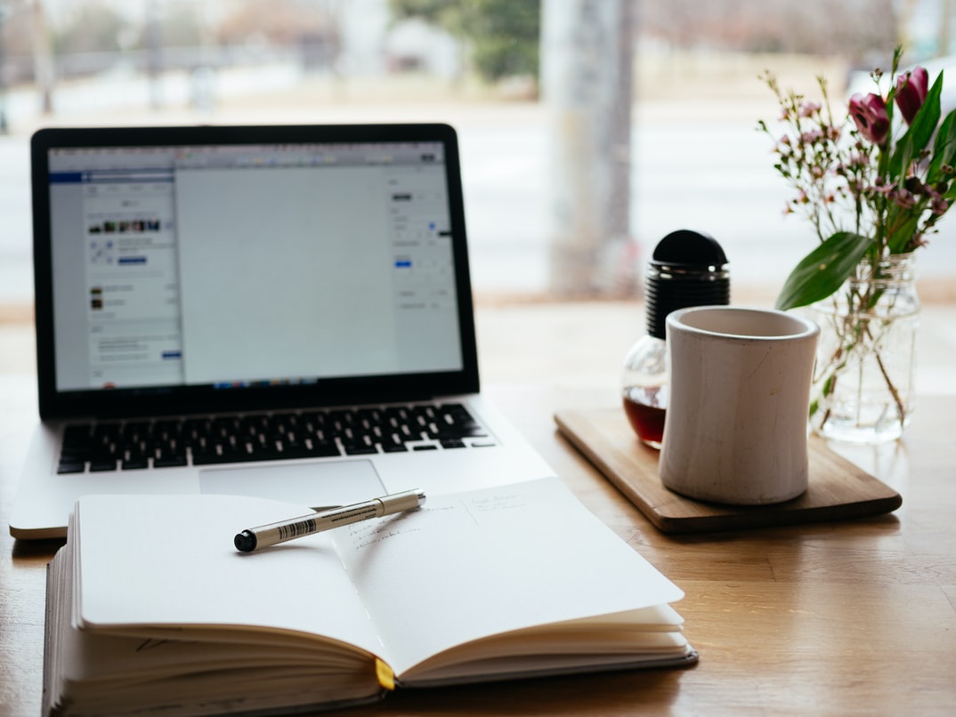 Laptop und Notizbuch und Kaffee auf einem Schreibtisch